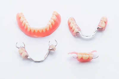 The image shows four pairs of dentures with red gums arranged on a white surface.