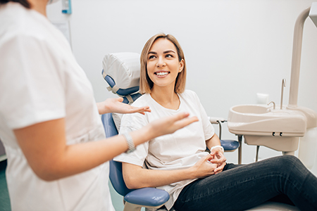 A woman sitting in a dental chair with a smile on her face, receiving dental care, surrounded by dental professionals.