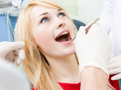 A woman receiving dental care with a dentist s hand holding a drill over her mouth.